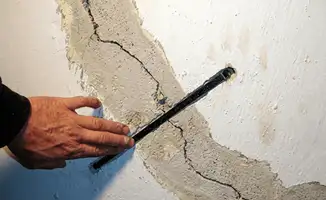A wall with a large crack is being inspected by a professional in Colorado Springs, CO